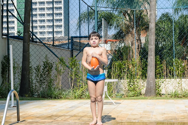 Niño de 8 años, con el pecho lleno de aire, dispuesto a saltar a la piscina con una bomba de agua.