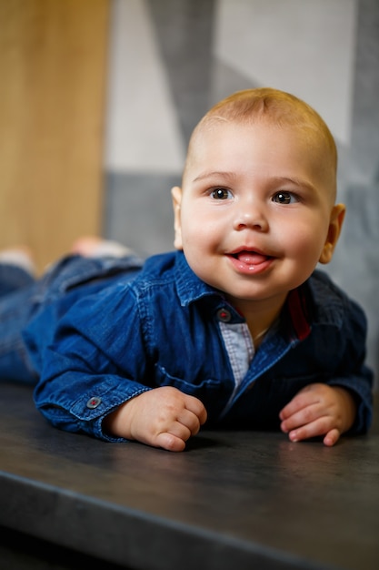 Niño de 8 meses en una chaqueta acostada boca abajo y hermosas sonrisas