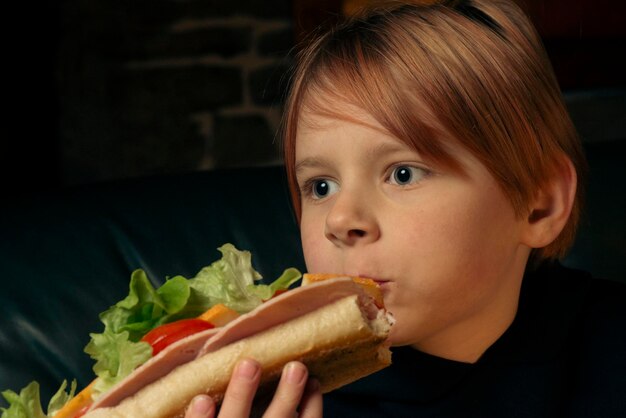 Niño de 9 años comiendo un sándwich de baguette grande