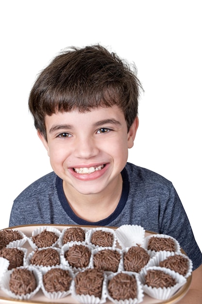 Niño de 9 años sosteniendo una bandeja con varias bolas de fudge brasileño y con una gran sonrisa