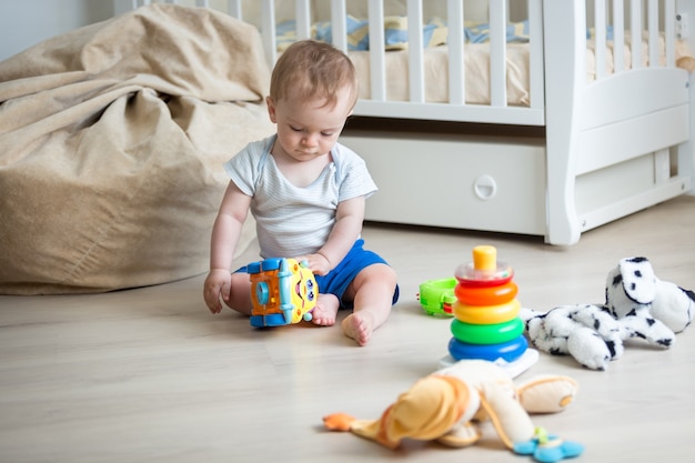 Niño de 9 meses jugando con coche de juguete y torre de juguete