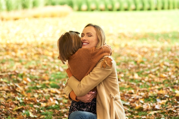 Foto niño abrazando a mamá en el bosque de otoño