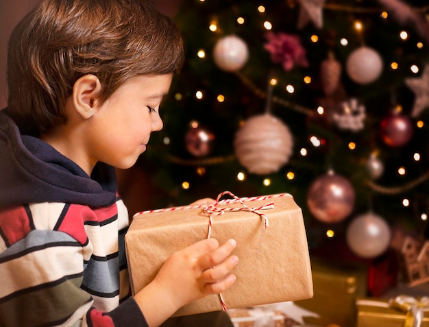 niño abre un regalo debajo del árbol