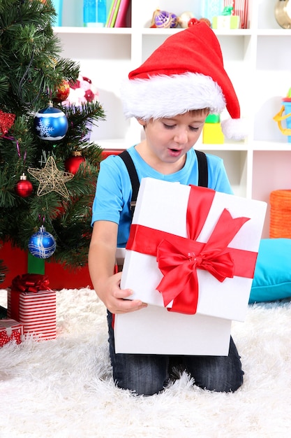 Niño abre sus regalos cerca del árbol de Navidad