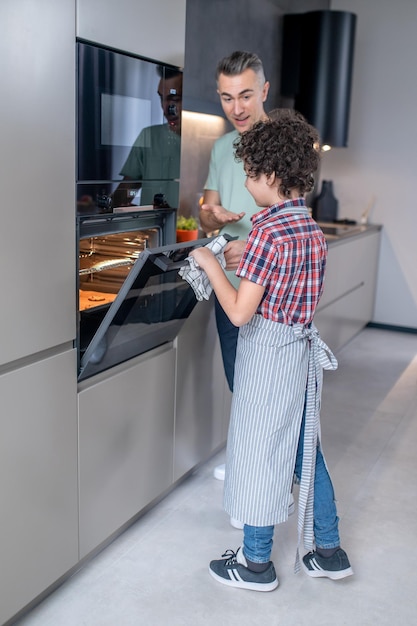 Niño abriendo horno y papá feliz cerca