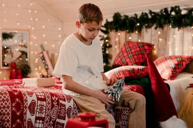 Un niño abriendo regalo de Navidad. Niño cerca del árbol de Navidad con cajas de regalo. Salón decorado. Humor navideño. Vispera de Año Nuevo.