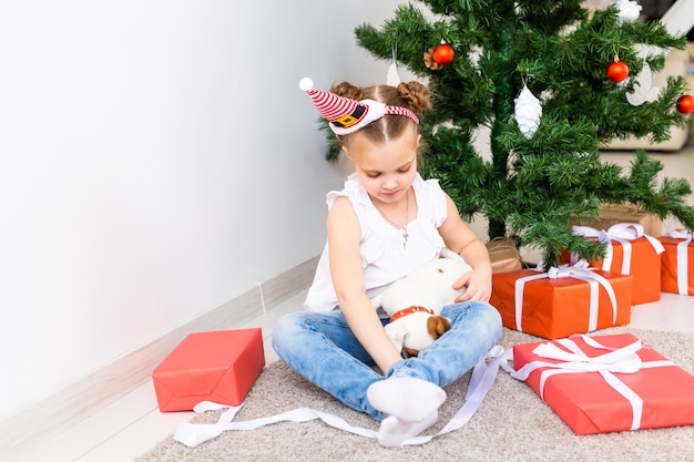 Niño abriendo regalos de Navidad. Niño bajo el árbol de Navidad con cajas de regalo.