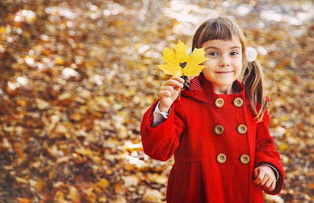 Foto niño en un abrigo rojo con hojas de otoño. me encanta el otoño enfoque selectivo