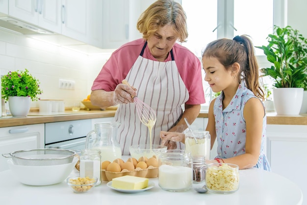 Niño y abuela en la cocina hornea prepara la masa en la cocina Enfoque selectivo Alimentos