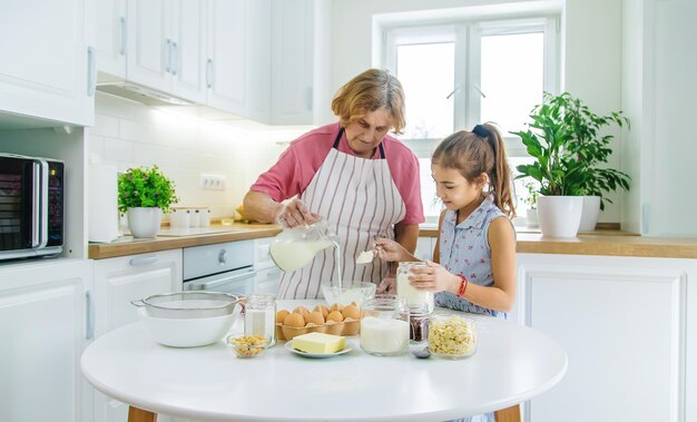 Niño y abuela en la cocina hornea prepara la masa en la cocina Enfoque selectivo