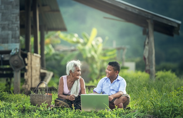 Niño y abuela felices usando una computadora portátil al aire libre