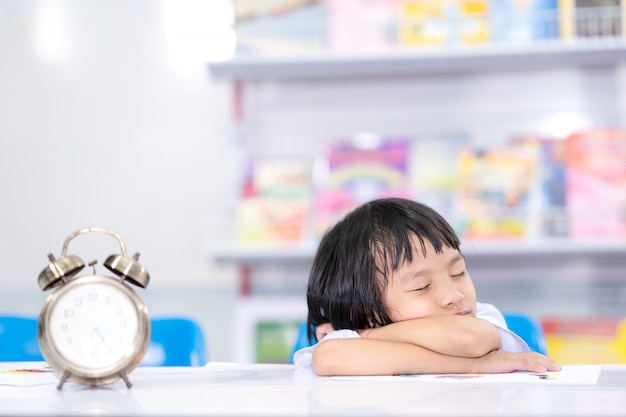 Foto niño aburrido aprender y estudiar para dormir en mesa