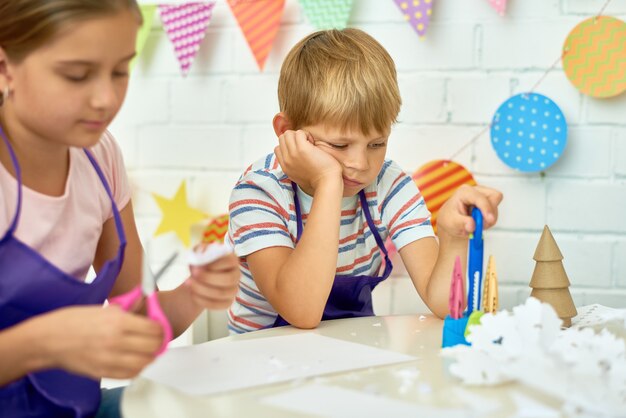 Niño aburrido en clase de artesanía