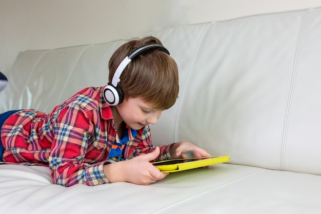 Niño acostado en la cama jugar la tableta