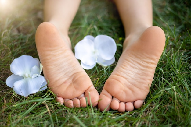 Niño acostado en la hierba en el parque en verano, primer plano de las piernas de los niños