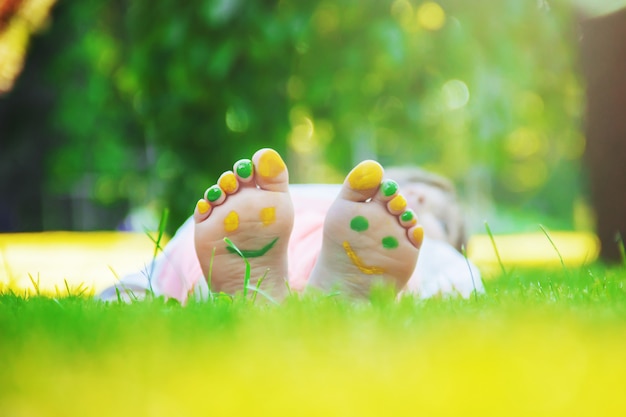 Niño acostado en la hierba verde. Niño divirtiéndose al aire libre en el parque de la primavera.