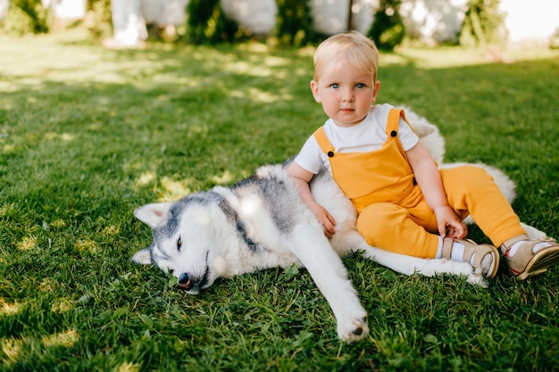 Un niño acostado con el perro en la hierba.