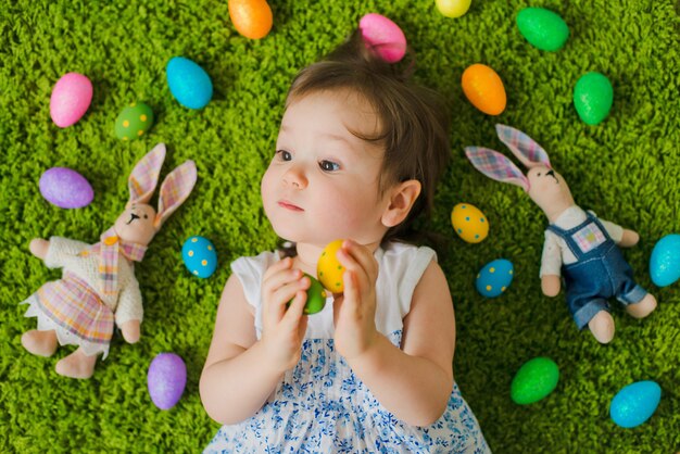 Niño se acuesta en la hierba con huevos de Pascua y una liebre