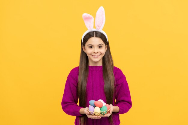 niño adolescente alegre en orejas de conejo sosteniendo coloridos huevos de pascua, huevo de pascua.