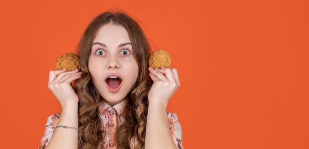 Niño adolescente asombrado con galletas de avena en el espacio de copia de fondo naranja