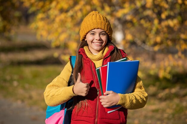 Niño adolescente feliz regreso a la escuela en otoño pulgar arriba