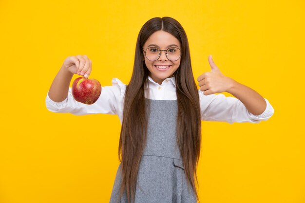 Niño adolescente con manzana sobre fondo amarillo aislado las manzanas son buenas para los niños Niña feliz se enfrenta a emociones positivas y sonrientes