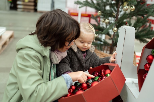 Niño adolescente con una niña pequeña mirando las decoraciones de Navidad en un gran supermercado
