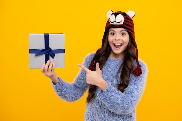Niño adolescente en ropa de invierno sosteniendo cajas de regalo celebrando feliz año nuevo o Navidad Vacaciones de invierno para niños Adolescente feliz emociones positivas y sonrientes de niña adolescente