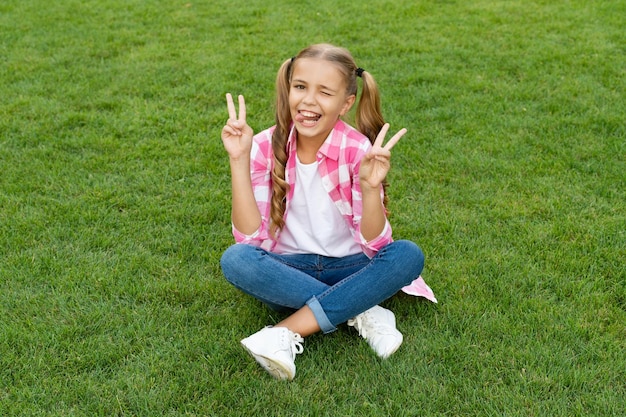 Niño adolescente sonriente sentarse en la hierba verde al aire libre