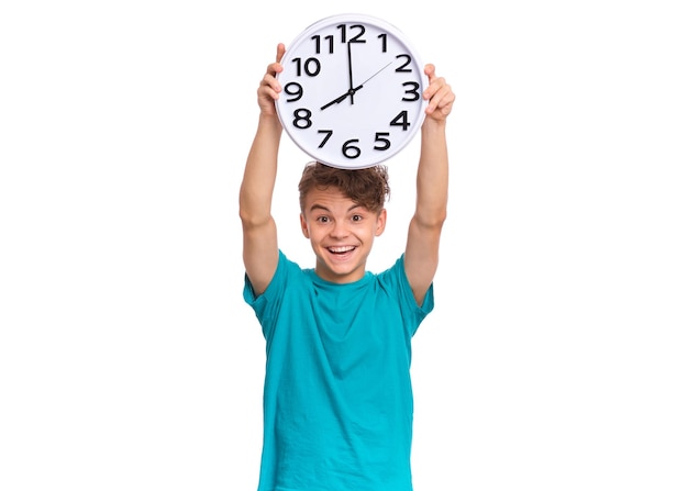 Niño adolescente sonriente sosteniendo un gran reloj aislado sobre fondo blanco Retrato de un adolescente divertido caucásico mostrando un gran reloj Niño feliz de regreso a la escuela Concepto de educación y tiempo