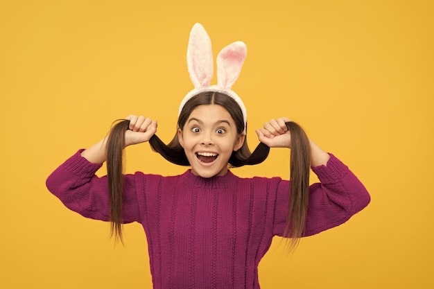 Niño adolescente sorprendido en orejas de conejo divirtiéndose en la diversión de vacaciones de Pascua