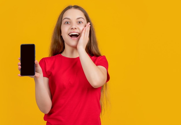 Niño adolescente sorprendido con smartphone sobre fondo amarillo