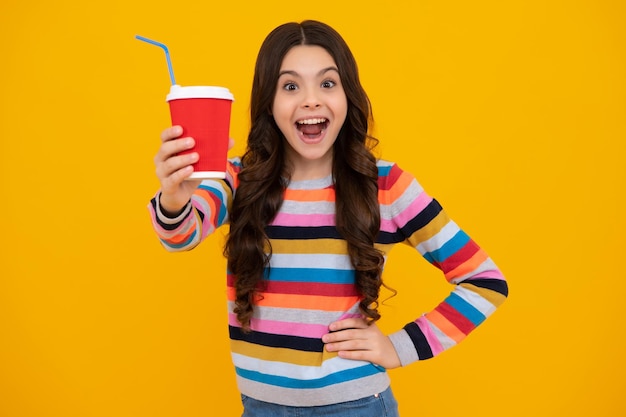 Niño adolescente con taza de café aislado sobre fondo amarillo de estudio Chica bebiendo bebida para llevar