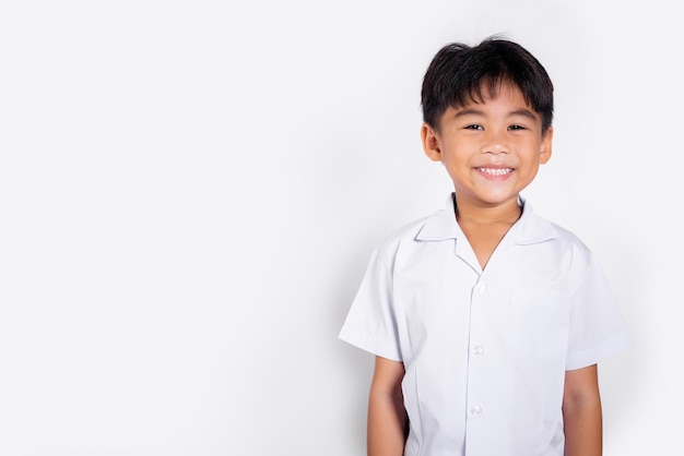 Niño adorable asiático sonriendo feliz vistiendo uniforme tailandés de estudiante de pie