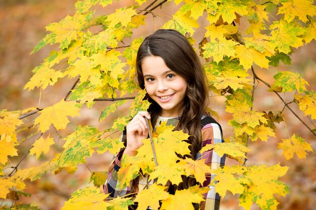 Niño adorable con bonita sonrisa disfruta de la temporada de otoño, la naturaleza.