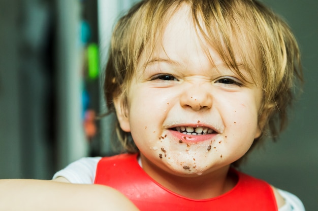 Niño adorable del retrato que come la torta de esponja del chocolate