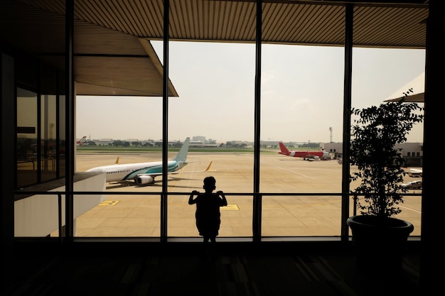 Niño en el aeropuerto de espera para la salida, imagen de filtro de color, el aeropuerto de viajes de negocios