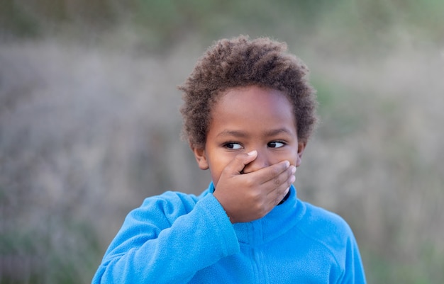 Niño africano cubriendo su boca