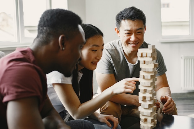 Niño africano y pareja asiática jugando jenga Jugar al juego de mesa en un tiempo libre