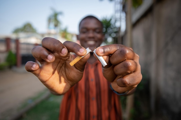 Niño africano rompe un cigarrillo en dos, lo hace por su propio concepto de dejar de fumar