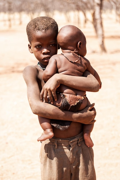 Niño Africano sosteniendo un bebé La tribu Himba Namibia