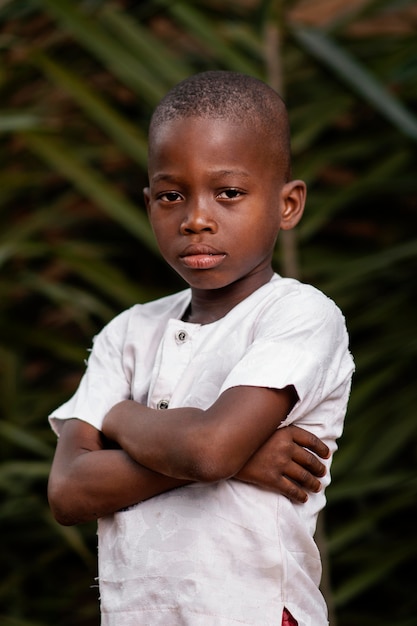 Foto niño africano de tiro medio posando con los brazos cruzados