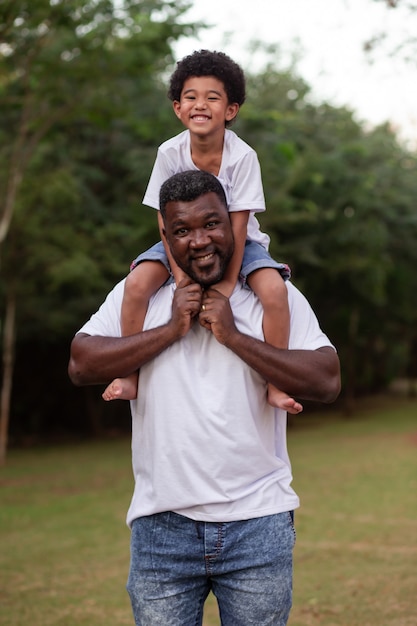 Niño afro con su padre en el parque en el cuello