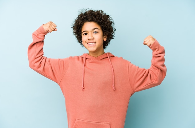 Niño afroamericano aislado mostrando gesto de fuerza con los brazos, símbolo del poder femenino