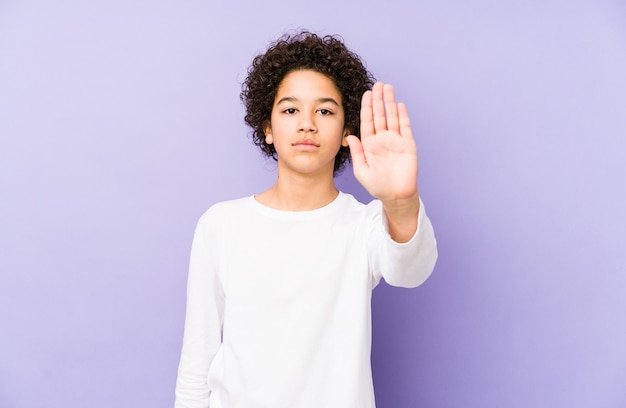 Niño afroamericano aislado de pie con la mano extendida mostrando la señal de stop, impidiéndote.