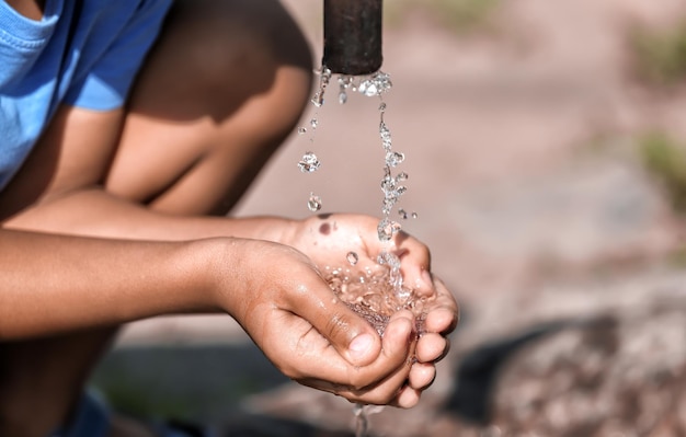 Foto niño afroamericano bebiendo agua del primer grifo