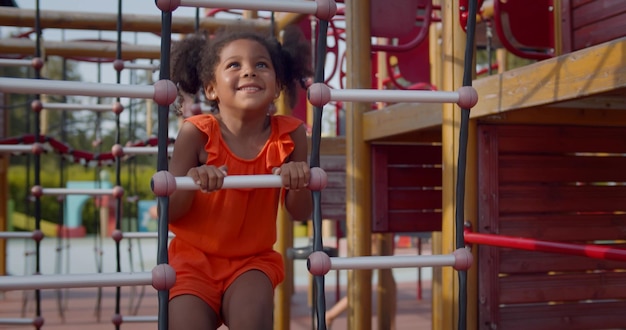 Niño afroamericano divirtiéndose con red de escalada al aire libre