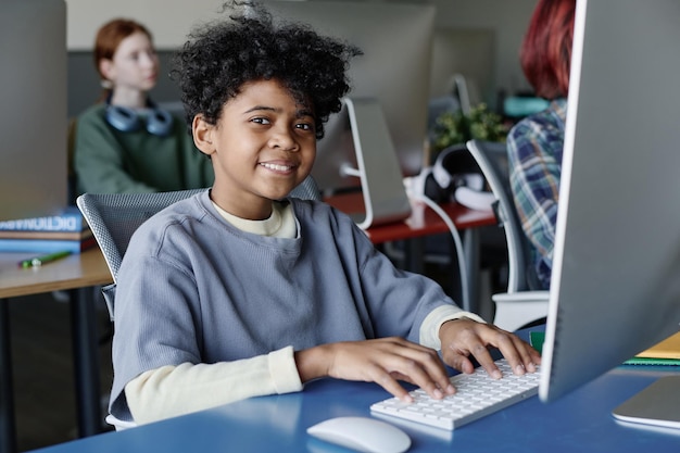 Un niño afroamericano escribiendo en la computadora en clase.