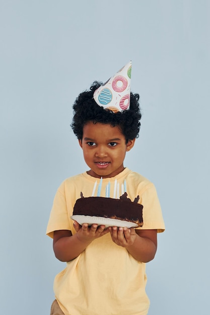 Un niño afroamericano feliz se divierte en el interior de la fiesta de cumpleaños con pastel