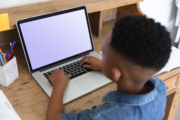 Niño afroamericano que tiene una videollamada usando una computadora portátil durante la clase en casa